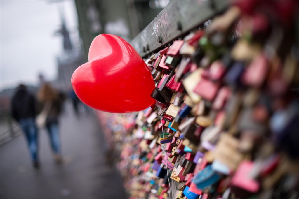 Ein roter Herzballon hängt am 14.02. zwischen Liebesschlössern an der Hohenzollernbrücke in Köln Ein roter Herzballon hängt am 14.02. zwischen Liebesschlössern an der Hohenzollernbrücke in Köln