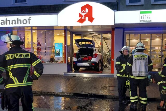 Ein Auto ist in den Eingang einer Apotheke gerast. Vor dem Eingang stehen mehrere Feuerwehrleute.