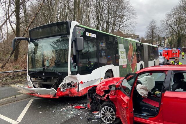 Ein rotes Auto mit demolierter Front steht nach einem Unfall in Dortmund neben einem ebenfalls beschädigten Linienbus.