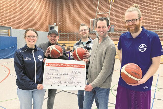 Eine junge Frau und fünf junge Männer mit Basketbällen und Spendenscheck in einer Sporthalle.