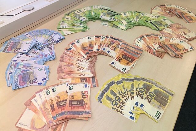 100.000 Euro Falschgeld und ein Koffer mit doppeltem Boden befinden sich auf einem Tisch.