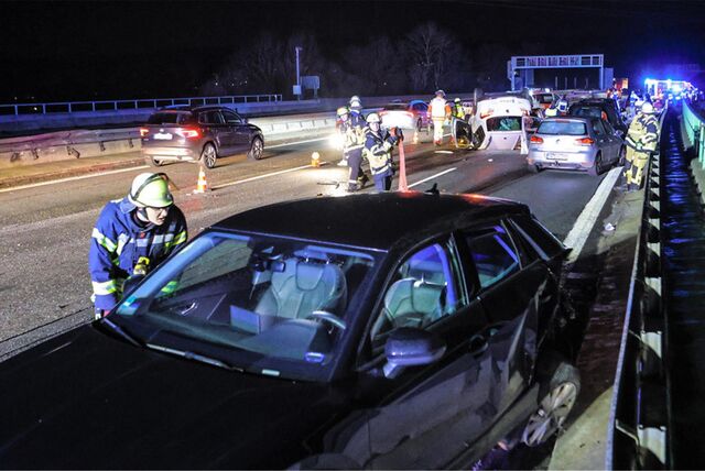 Feuerwehrleute stehen an den verunglückten Autos: Mehrere Fahrzeuge waren am Samstagabend (10.2.) an zwei Unfällen auf der A45 in Höhe Schwerte-Ergste beteiligt.