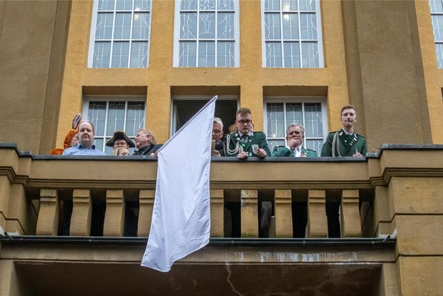 Eine Gruppe Menschen schwenkt eine weiße Fahne von einem Balkon.