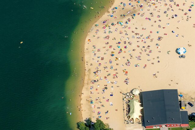 Der Strand am Silbersee II an einem Sommertag von oben gesehen, viele Badedecken, Sonnenschirme und Badegäste sind zu sehen, auch das Lokal Treibsand.