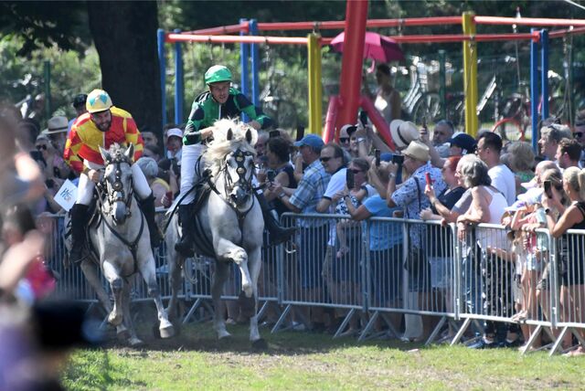 Zwei Reiter reiten auf ihren Pferden beim Castroper Pferderennen um die Wette.