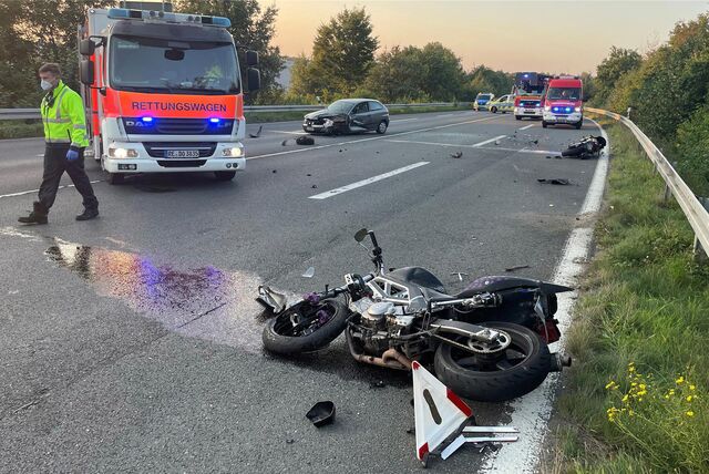Ein zerstörtes Motorrad liegt nach einem Unfall auf der L608 in Dorsten. Im Hintergrund sind ein weiteres zerstörtes Motorrad und ein beschädigtes Auto sowie Einsatzfahrzeuge von Polizei, Feuerwehr und Rettungsdienst zu sehen.