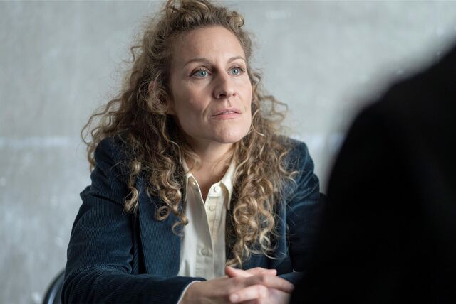 Die Schauspielerin Alessija Lause sitzt mit zusammengefalteten Händen an einem Tisch und spricht mit einer unkenntlichen Person.