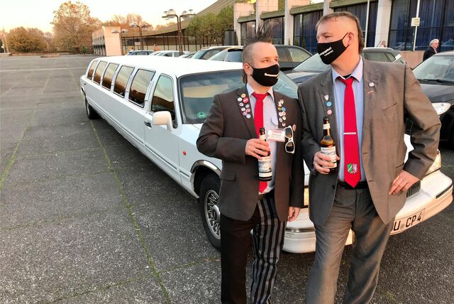 Andreas Kemna und Marcus Liedschulte sitzen jetzt für Die Partei im Rat und fordern erhöhte Gebühren für SUVs. Sie stehen vor einer weißen Stretch-Limo mit Bier in der Hand vor der Europahalle.