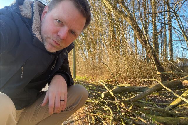 Reporter Tobias Weckenbrock hockt am Straßenrand und zeigt einen vom Sturm umgestürzten Baum, den die Feuerwehr in den frühen Morgenstunden mit der Säge zerlegte.