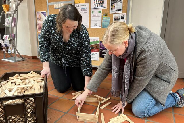Diakonin Lena Schäfer und Pfarrerin Merle Vokkert bauen mit Holz.