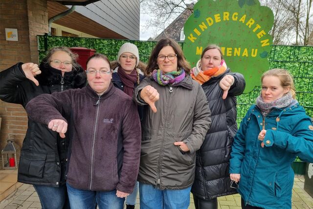 Frauen stehen vor einem Kita-Eingangsschild.