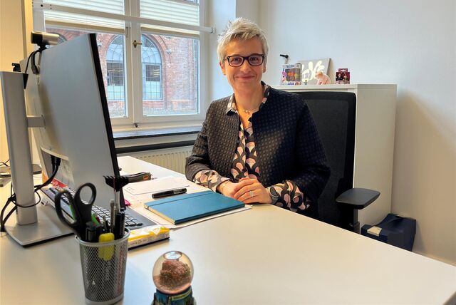 Leslie Czienienga an ihrem Schreibtisch bei Prosoz. Durchs Fenster sieht man die Backsteingebäude der ehemaligen Zeche Ewald.