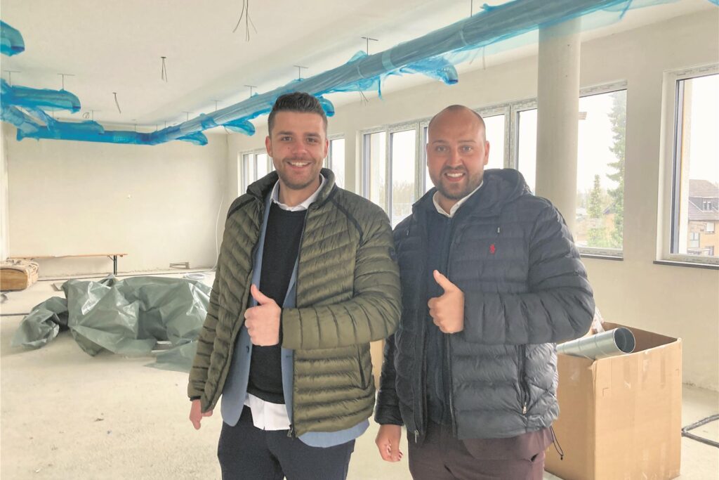 Zwei Männer auf einer Baustelle mit Daumen hoch.