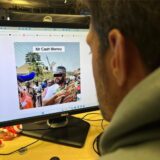 Ein Mann sitzt vor einem Computer-Monitor, auf dem ein Foto von „Mr. Cash Money“ zu sehen ist.