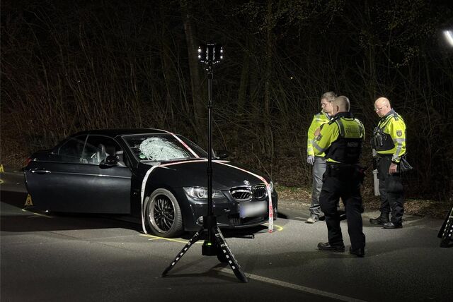 Polizisten stehen in der Dunkelheit vor einem beschädigten Unfallwagen in Recklinghausen.