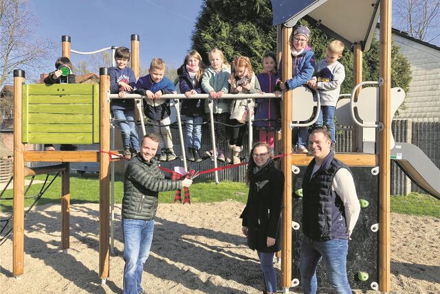 Bürgermeister Marcel Mittelbach gibt ein Spielgerät frei, auf dem viele Kinder stehen.