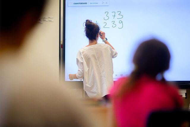 Eine Lehrerin schreibt etwas an ein Whiteboard.