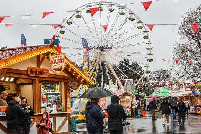 Besucher gehen bei der Osterkirmes „Fredolino“ in Dortmund über den Kirmesplatz am Fredenbaum.