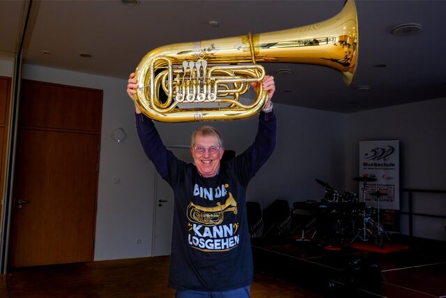Gerd Kluth aus Marl steht in einem Probenraum der Musikschule Recklinghausen, er hebt eine Tuba in die Luft.