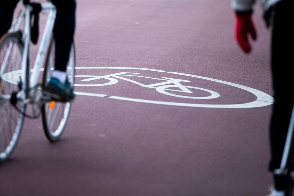 Zu sehen ist ein Fahrrad, ein Radweg und ein Symbol, das auf den Fahrradweg hinweist. Zu sehen ist ein Fahrrad, ein Radweg und ein Symbol, das auf den Fahrradweg hinweist.