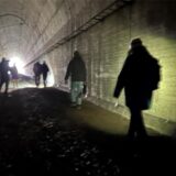 Mehrere Menschen gehen durch einen Tunnel, sie sind von hinten als Schattenrisse zu erkennen. Am Ende des Tunnels ist Tageslicht zu erkennen.