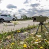 Ein mobiles Radargerät am Straßenrand und ein vorbeifahrendes Auto.