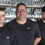 Drei Männer mit schwarzen T-Shirts.