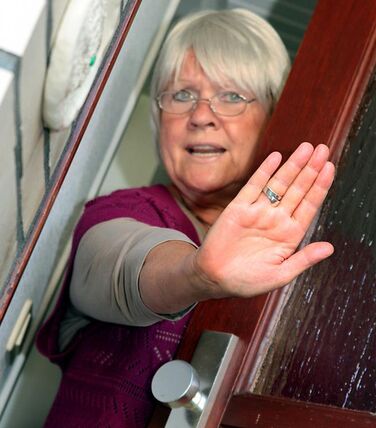 Eine Seniorin verwehrt jemandem den Zutritt zu ihrer Wohnung.