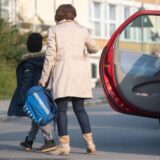 Eine Mutter, die ihr Kind mit dem Auto zur Schule bringt.