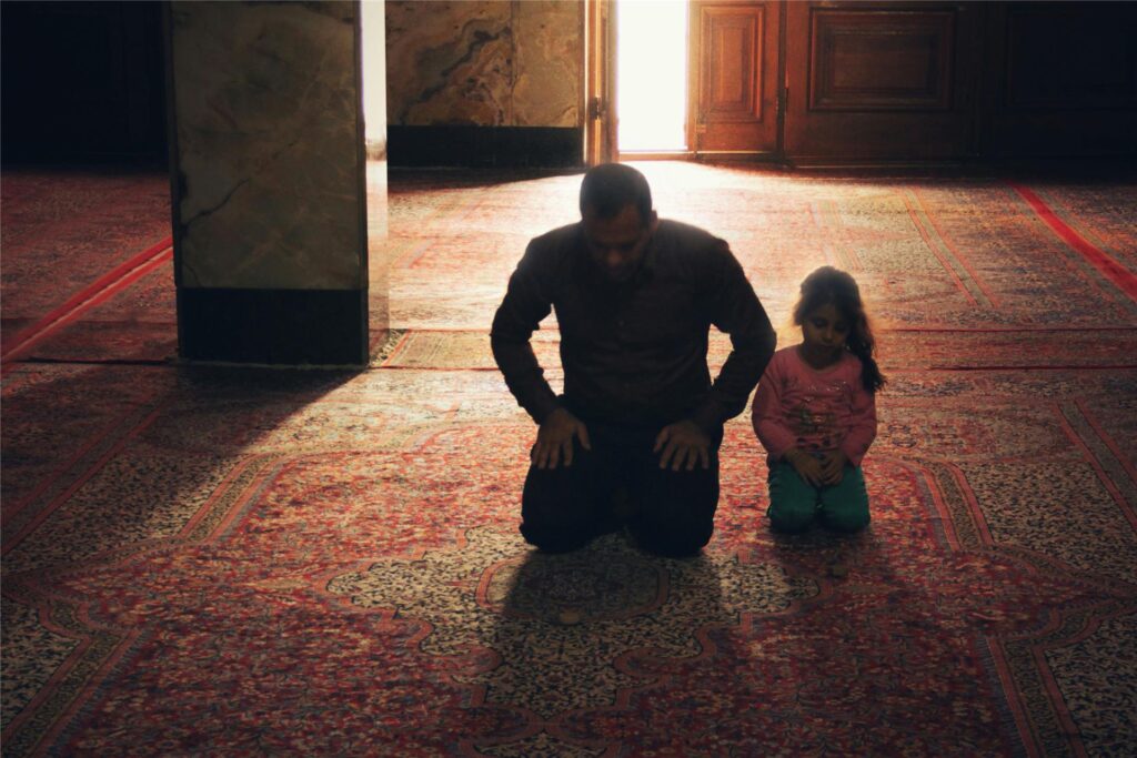 Ein Vater und seine Tochter knien während des Ramadan in einer Moschee und beten.