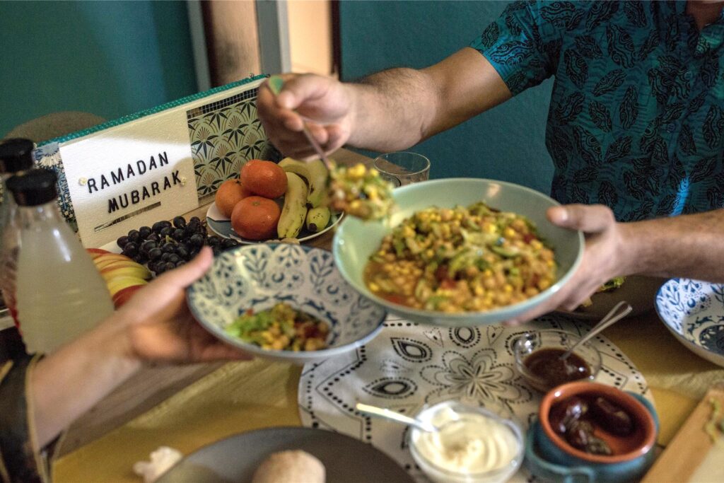 Ein Mann füllt seiner Frau beim Fastenbrechen (Iftar) Salat auf ihren Teller.