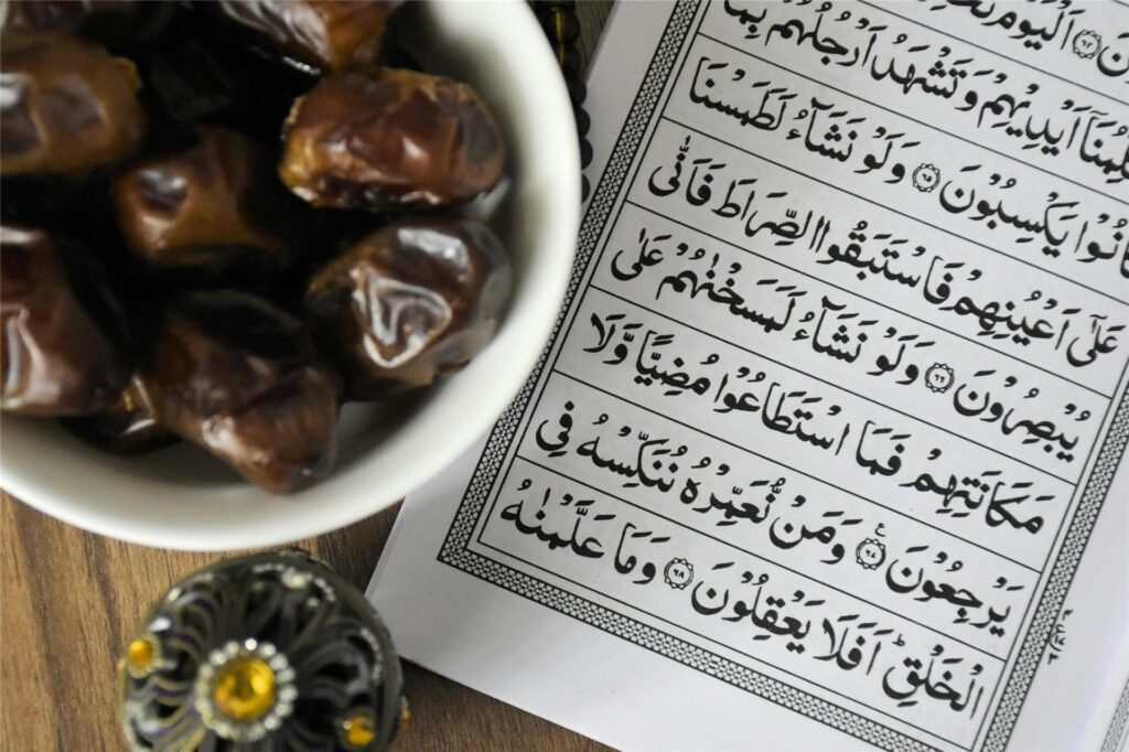 Eine Schale mit Datteln steht auf einem Tisch, daneben liegt ein muslimisches Gebetbuch. Eine Schale mit Datteln steht auf einem Tisch, daneben liegt ein muslimisches Gebetbuch.