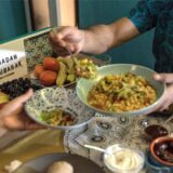 Ein Mann füllt seiner Frau beim Fastenbrechen (Iftar) Salat auf ihren Teller.