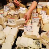 Eine Mitarbeiterin eines Bioladens sortiert an der Käsetheke verschiedene Sorten Käse.