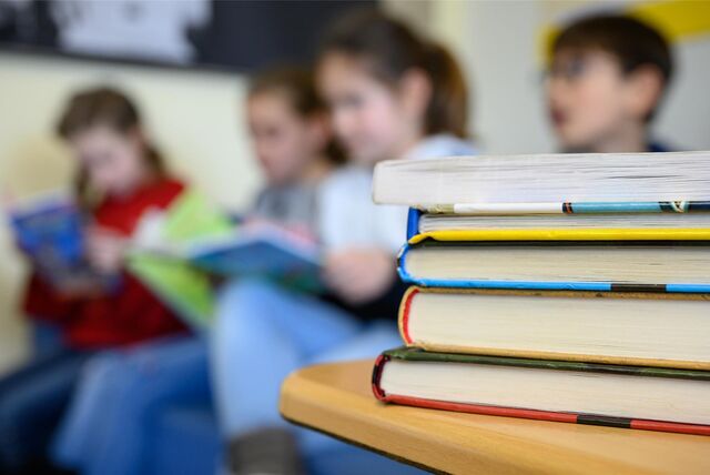 Vier Kinder lesen hinter einem Stapel Bücher. (Symbolbild)