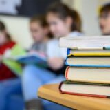 Vier Kinder lesen hinter einem Stapel Bücher. (Symbolbild)