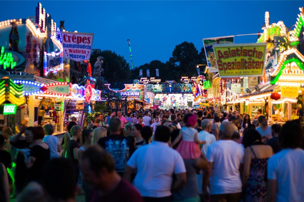 Besucher laufen am Abend über eine Kirmes. Besucher laufen am Abend über eine Kirmes.