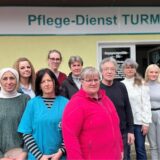 Karl Liebig und einige seiner Mitarbeiterinnen stehen vor der Eingangstür zum Pflegedienst Turmalin in Castrop-Rauxel.