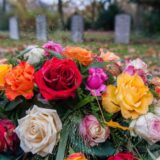 Ein Rosengesteck liegt auf einem Friedhof.