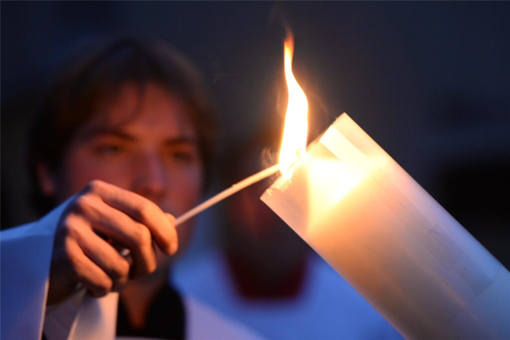 Ein Messdiener zündet in der Osternacht die Osterkerze an. Ein Messdiener zündet in der Osternacht die Osterkerze an.