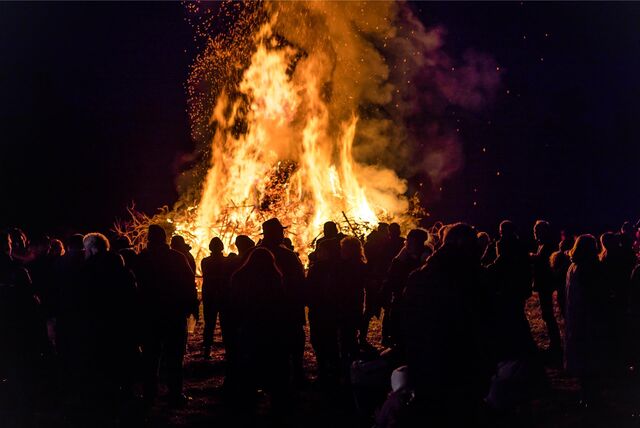 Mehrere Personen stehen vor einem brennenden Osterfeuer.