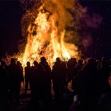 Mehrere Personen stehen vor einem brennenden Osterfeuer.
