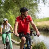 Symbolbild: Zwei Radfahrer fahren an einem Fluss entlang.
