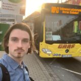 Ein Reporter der Ruhr Nachrichten steht vor dem RB43-Schienenersatzverkehr-Bus am Hauptbahnhof in Dortmund.