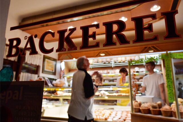 „Bäckerei“ ist am Schaufenster einer Bäckerei zu lesen, in der ein Kunde von zwei Mitarbeitern bedient wird.
