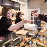 Eine Verkäuferin nimmt in einer Bäckerei in Duisburg (NRW) Bargeld von einem Kunden entgegen.