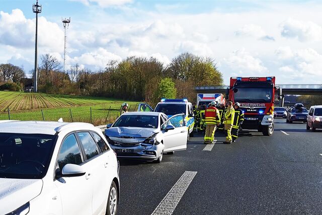 Ein verbeulter Pkw, Rettungsfahrzeuge und Polizeibeamte stehen auf der Autobahn, während der Verkehr auf der anderen Fahrspur vorbeigeführt wird.