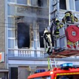 Feuerwehreinsatz in Solingen: Feuerwehrmänner stehen auf einer Drehleiter vor dem Mehrfamilienhaus, in dem es gebrannt hat.