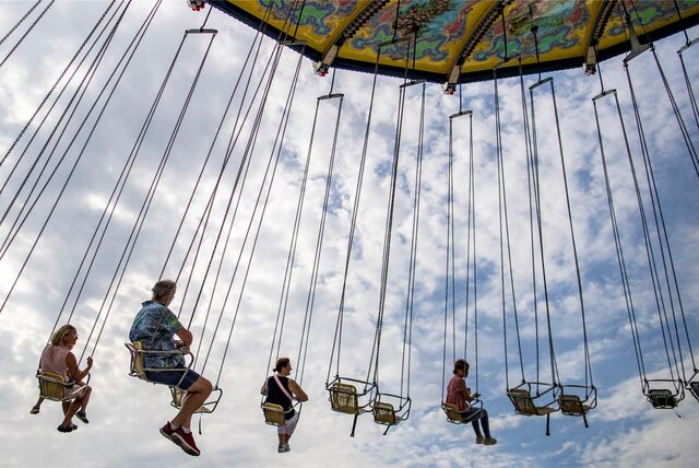Menschen sitzen auf einer Kirmes in einem Kettenkarussell.