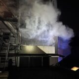 Dichter Rauch dringt bei einem Feuer in einem Wohnhaus aus der Gebäuderückseite heraus.